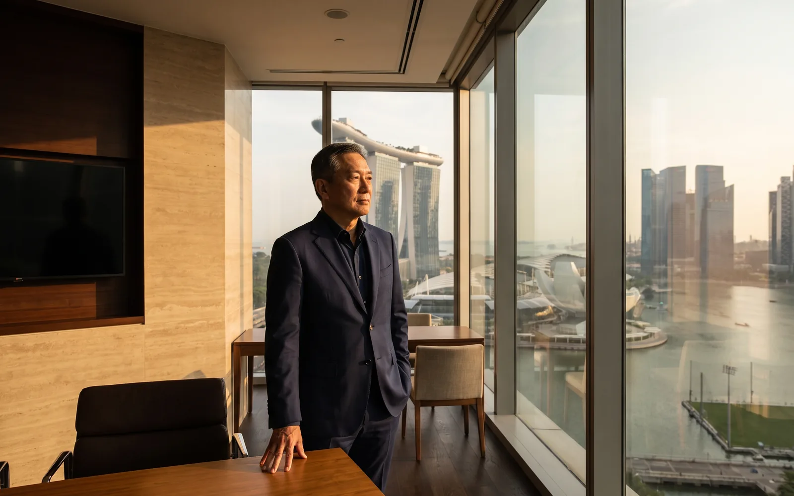 A senior executive in a calm, light-filled Singapore office, the business district beyond the glass